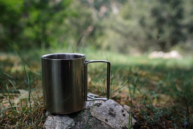 Une tasse avec une boisson chaude se dresse sur une pierre dans la nature