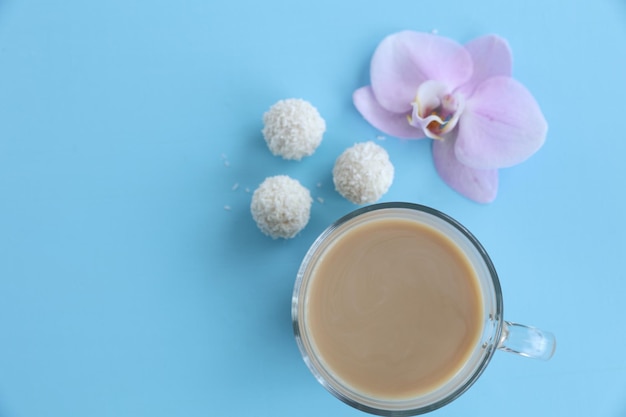 Une tasse de bonbons au café et d'orchidée sur fond bleu