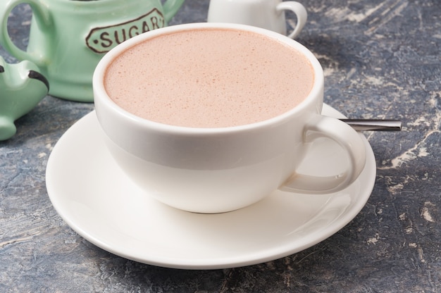 Tasse de cacao blanc avec du lait sur fond gris