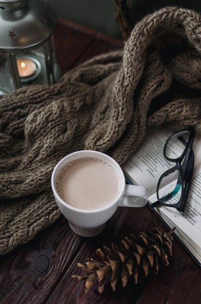 Tasse de cacao blanc sur une vieille table en bois avec un livre amusant et des lunettes de lecture.