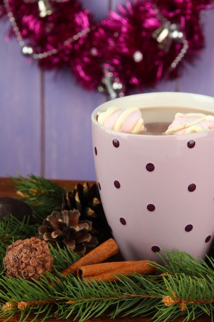 Tasse de cacao chaud avec des chocolats et des branches de sapin sur table sur fond de bois