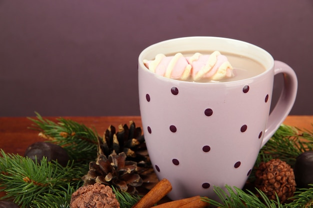 Tasse de cacao chaud avec des chocolats et des branches de sapin sur la table