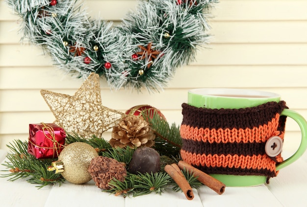 Tasse de cacao chaud avec des chocolats et des décorations de Noël sur table sur fond de bois