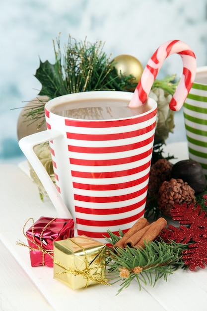 Tasse de cacao chaud avec chocolats et décorations de Noël sur table sur surface lumineuse