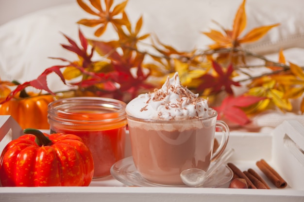 Tasse de cacao chaud et crémeux avec mousse, citrouilles et feuilles sèches