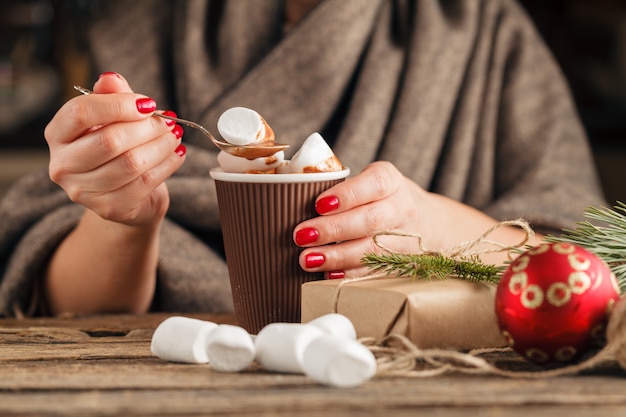 Tasse de cacao et de guimauve entre les mains de la jeune fille. Ongle gel manucure.