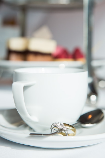 Tasse de café, alliances en cuillère sur table