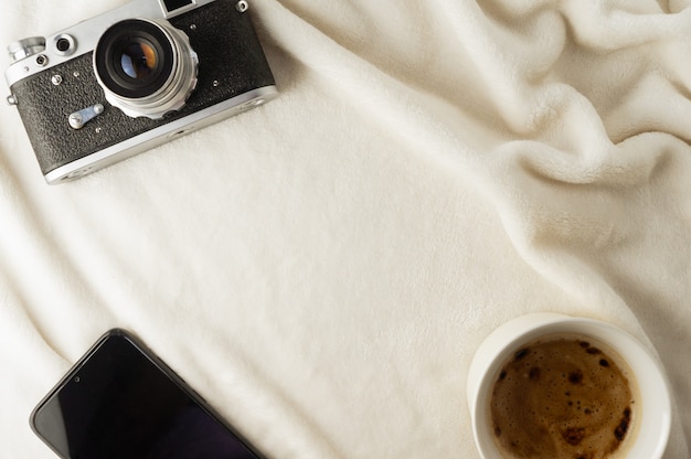 Tasse de café appareil photo et smartphone sur une couverture douce