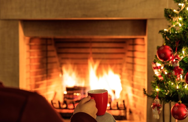 Photo tasse de café sur l'arbre de noël et fond de cheminée en feu