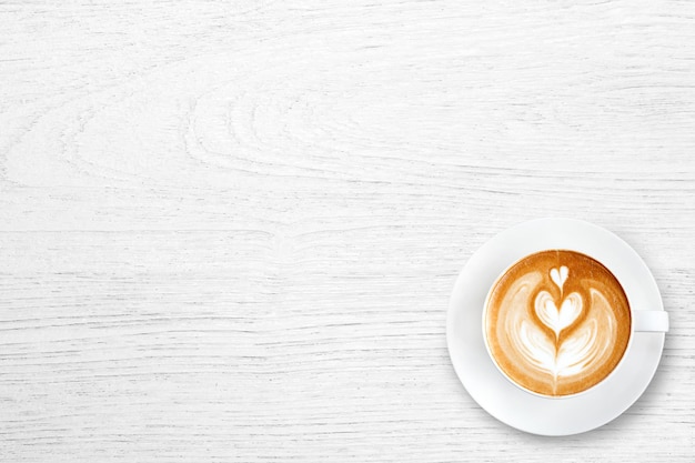 Tasse de café au lait avec coeur sur une table en bois blanche