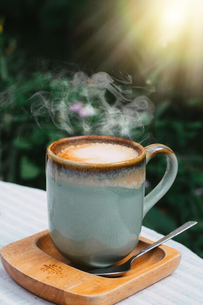 Tasse de café au lait dans une tasse de poésie verte sur fond de bois ancien au soleil du matin