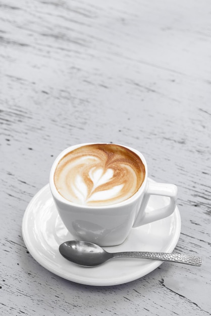 Une tasse de café au lait sur une table en bois blanc