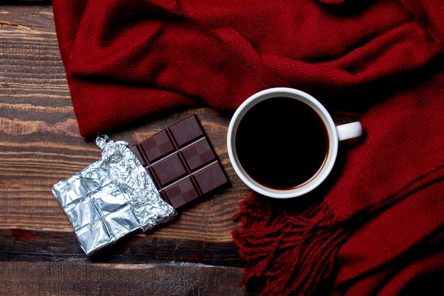 Tasse de café et barre de chocolat avec foulard sur table en bois