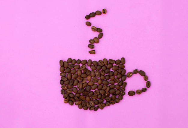 Une tasse de café à base de grains. Composition avec une tasse de café et de la vapeur de grains. Une tasse de grains de café avec de la fumée, sur fond rose. Espresso ou cappuccino chaud à base de haricots.