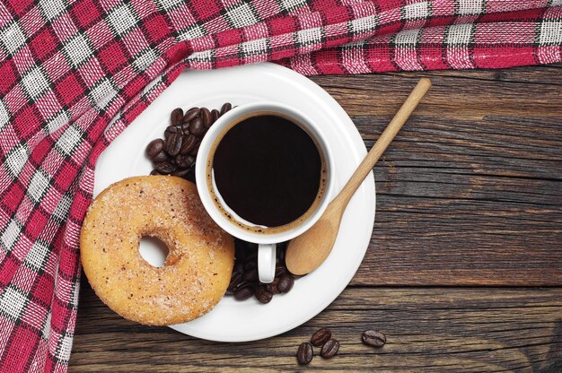 Tasse à café et beignet sur table en bois avec nappe rouge, vue de dessus