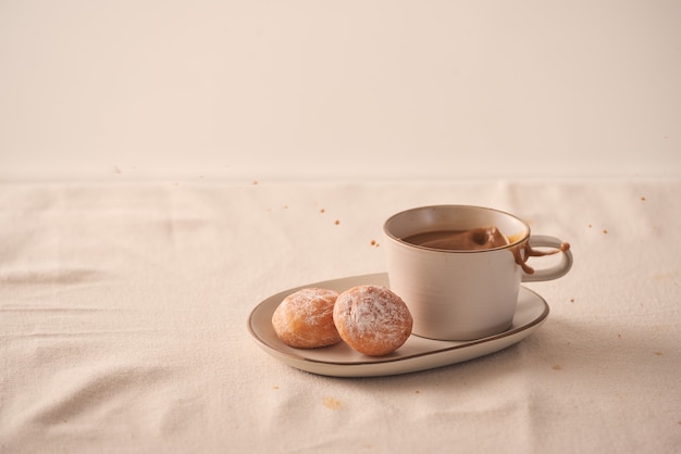 Tasse de café avec des beignets pour le petit déjeuner sur fond clair