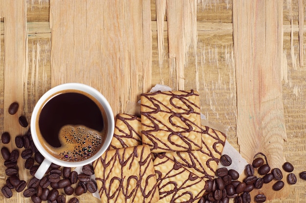 Tasse à café et biscuits au chocolat carrés sur une vieille table en bois, vue de dessus