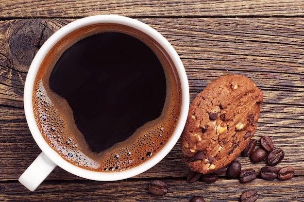 Tasse à café et biscuits au chocolat avec des noix sur la vieille table en bois