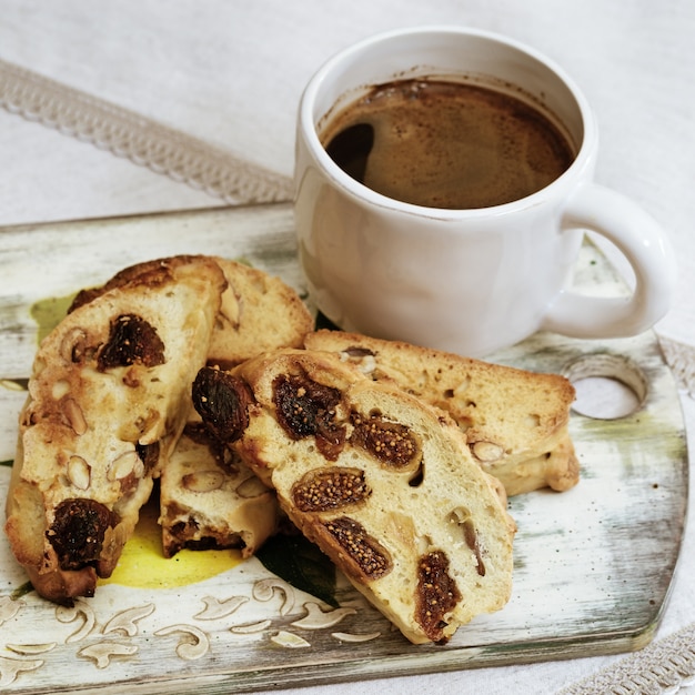 Tasse à café et biscuits biscotti sur planche de bois.