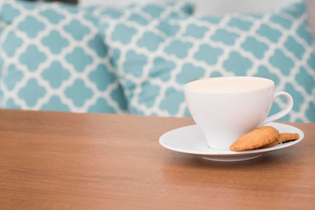 Une tasse de café avec des biscuits dans une assiette sur une table en bois à la maison