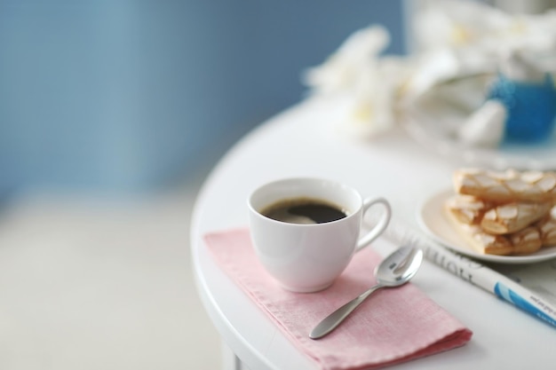 Tasse de café avec des biscuits sur une table blanche à l'intérieur clair