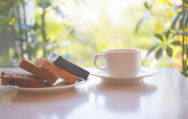 Tasse à café blanche avec assiette à pain sur la table avec la lumière du soleil en arrière-plan