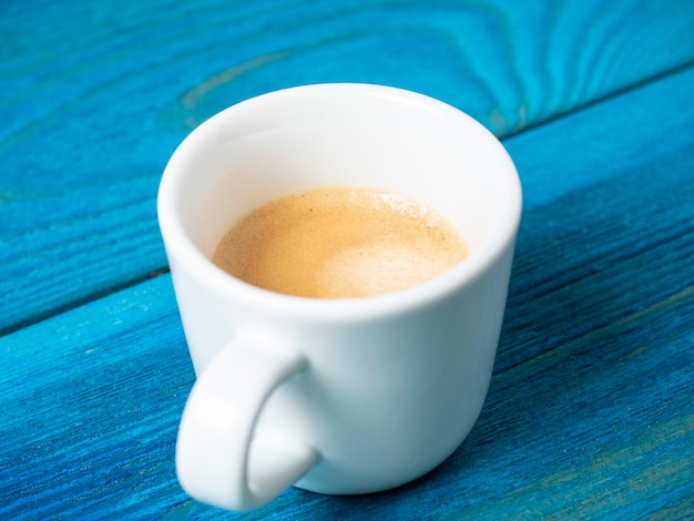 Tasse à café blanche avec expresso versé sur un fond en bois bleu. Café, boisson énergisante