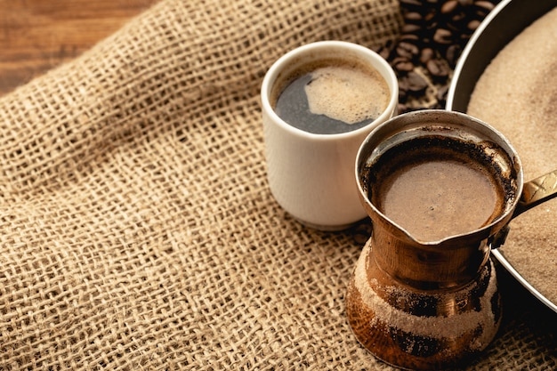 Tasse à café blanche avec des grains torréfiés sur un sac