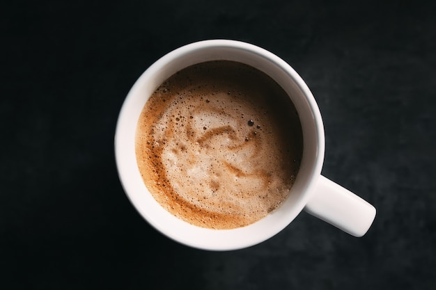 Tasse à café blanche sur le gris foncé