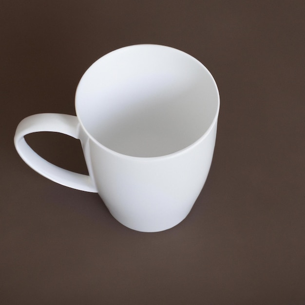 Une tasse à café blanche avec une poignée sur un fond marron