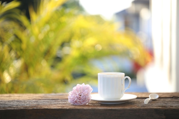 Tasse à café blanche et rose rose sur le balcon extérieur de table en bois