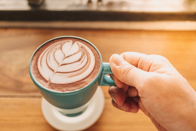 Tasse de café bleu avec plein d'art latte sur table en bois