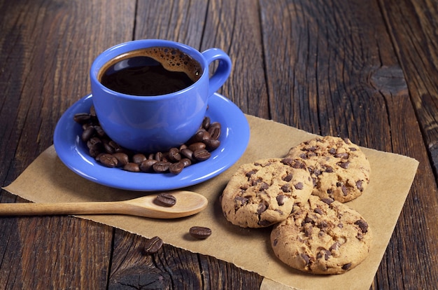 Tasse à café bleue et biscuits au chocolat sur une vieille table en bois