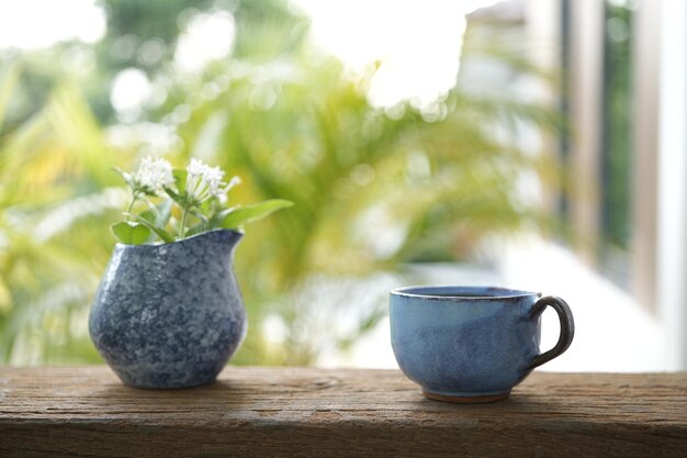 Tasse à café bleue et fleur blanche dans un vase bleu