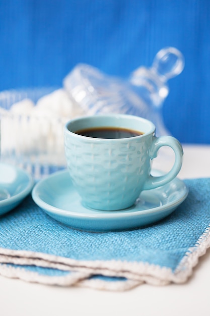 Tasse à café bleue et soucoupe à la guimauve sur des serviettes