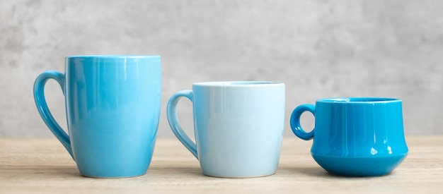 Tasse à café bleue et tasse à thé sur fond de table en bois le matin, espace de copie vierge pour le texte. Journée internationale du café et concept de routine quotidienne