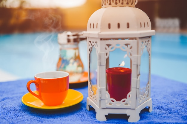 Photo tasse à café et bougie au bord de la piscine de l'hôtel