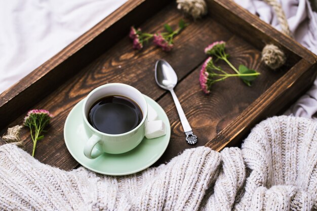 Tasse de café et bougie sur plateau de service en bois rustique et tricoter un pull en laine chaud