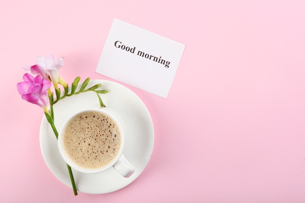 Une tasse de café un bouquet de fleurs et une carte avec les mots bonjour