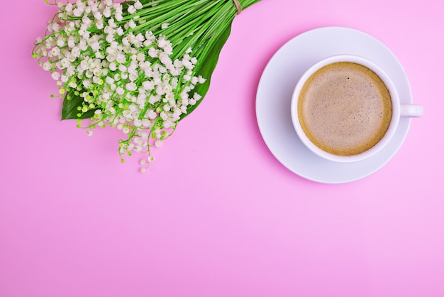 Tasse de café et un bouquet de lis blancs de la vallée