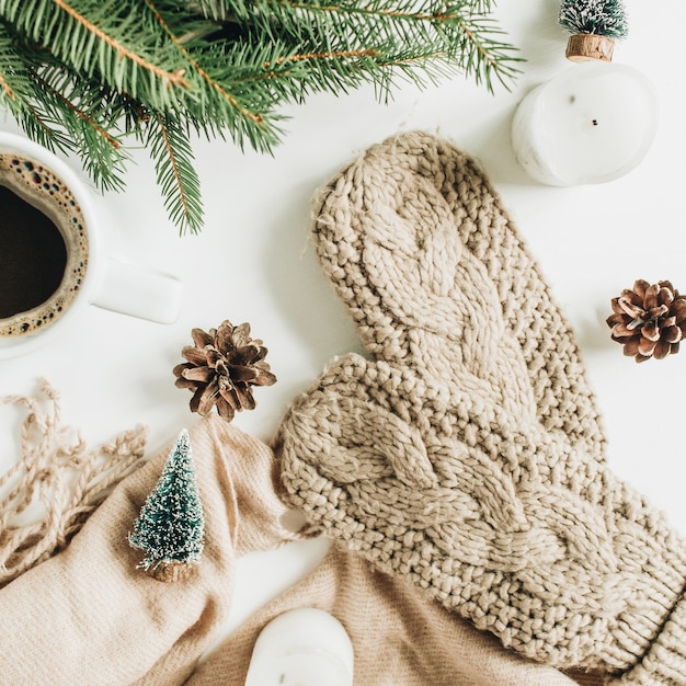 Tasse à café, branches de sapin, mitaines tricotées, couverture beige et décorations. Composition de vacances de Noël. Mise à plat, vue de dessus