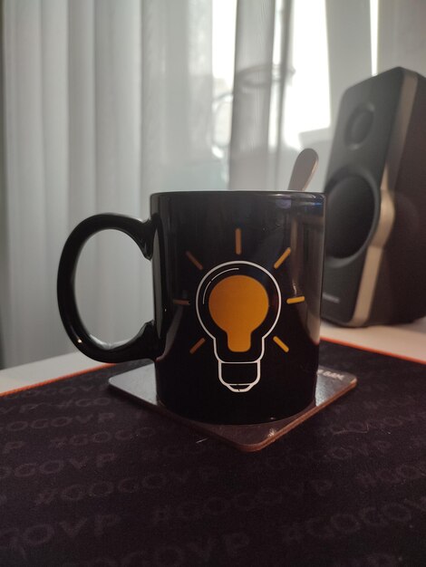 Photo une tasse de café sur le bureau avec une ampoule allumée. j'ai une idée.