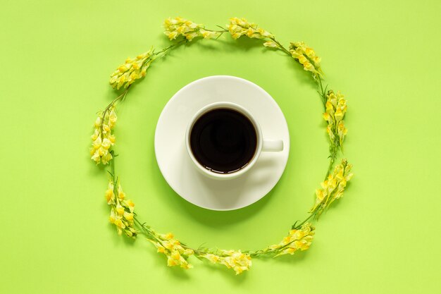 Tasse de café et cadre circulaire jaune fleurs sauvages Linaria sur fond vert Concept Bonjour ou Bonjour printemps