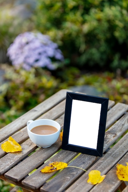 Tasse de café et cadre pour photo sur une table dans le jardin