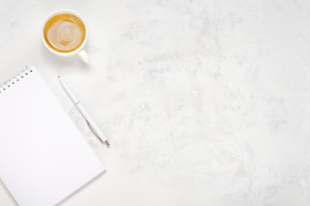 Tasse de café, cahier ouvert et stylo sur un fond de béton clair. Vue de dessus du lieu de travail. Copier l'espace