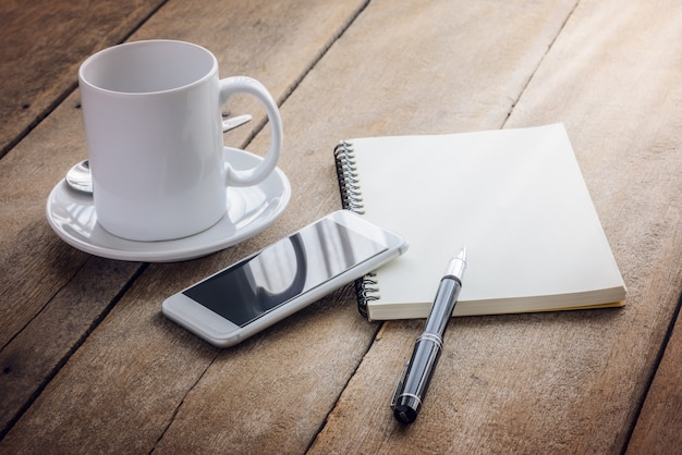 Tasse de café, cahier, stylo et téléphone intelligent