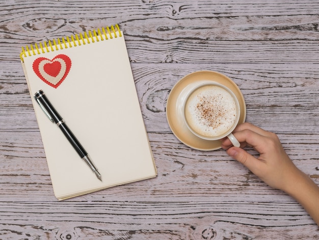 Une tasse de café avec de la cannelle et du lait et un ordinateur portable sur une table en bois