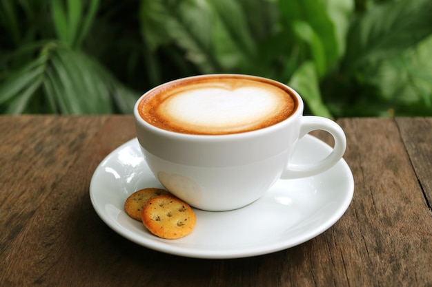 Tasse de café cappuccino avec biscuits servis sur table en bois dans le jardin