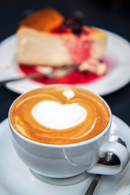 Tasse de café cappuccino et morceau de gâteau au fromage sur la table