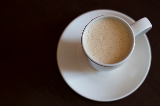 Une tasse de café cappuccino sur une table brune